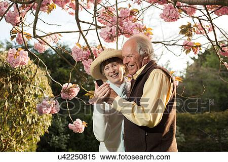 Senior couple smiling at message on mobile phone View Large Photo Image Stock Photography - Senior couple smiling at message on mobile phone. Fotosearch