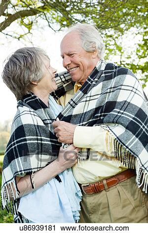 Stock Image - Senior couple wrapped in shawl together. Fotosearch