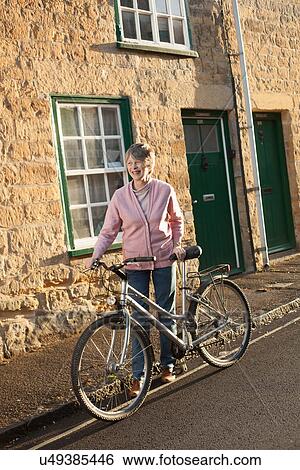 Stock Photograph - Senior man pushing his bicycle on street. Fotosearch