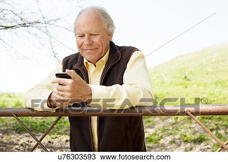Senior man smiling at message on mobile phone View Large Photo Image Stock Image - Senior man smiling at message on mobile phone. Fotosearch