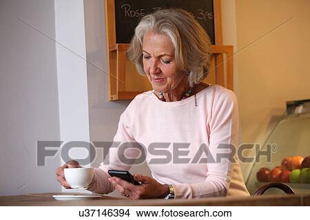 Senior woman holding coffee cup and mobile phone View Large Photo Image Picture - Senior woman holding coffee cup and mobile phone. Fotosearch