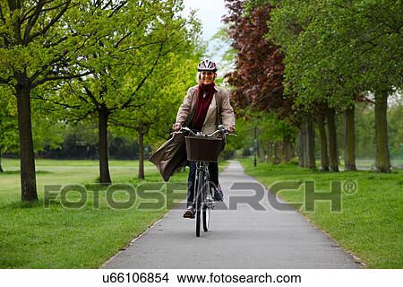 Senior woman riding bicycle in park View Large Photo Image Picture - Senior woman riding bicycle in park. Fotosearch