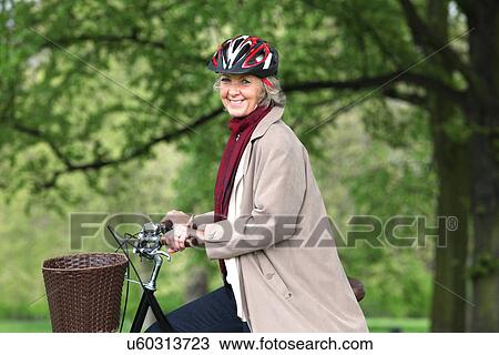 Senior woman riding bicycle in park, portrait View Large Photo Image Stock Image - Senior woman riding bicycle in park, portrait. Fotosearch