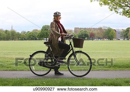 Senior woman riding bicycle in park, portrait View Large Photo Image Stock Photo - Senior woman riding bicycle in park, portrait. Fotosearch