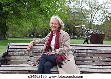 Stock Image - Senior woman sitting on park bench, portrait. Fotosearch