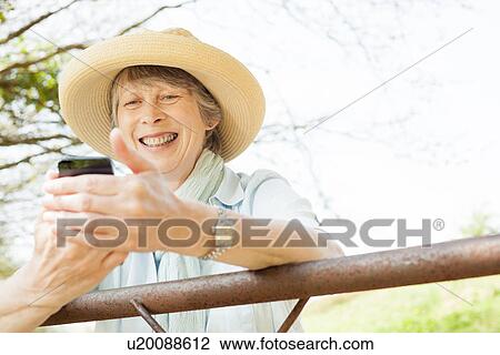 Senior woman smiling at message on mobile phone View Large Photo Image Stock Image - Senior woman smiling at message on mobile phone. Fotosearch