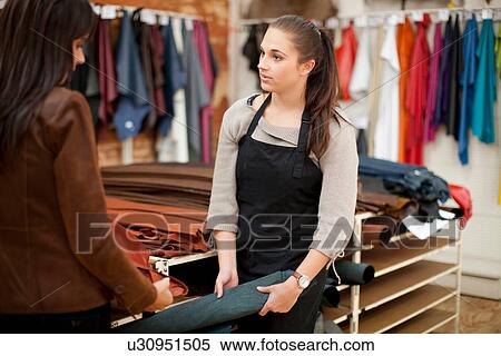 Stock Photography - Shop assistant and customer looking at roll of leather. Fotosearch