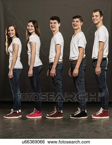 Stock Photograph - Side view of five teenagers standing in a group, smiling. Fotosearch
