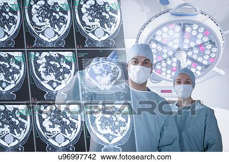 Stock Image - Surgeons discussing computed tomography (CT) scans in operating theatre. Fotosearch