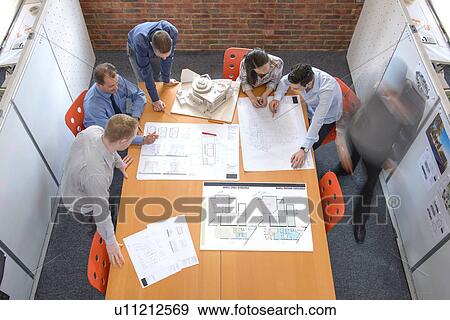 Stock Photo - Team of architects discussing plans in meeting room, blurred motion. Fotosearch