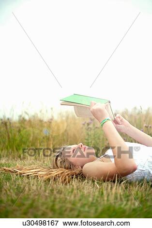 Teen girl lying in field, reading book View Large Photo Image Stock Photo - Teen girl lying in field, reading book. Fotosearch