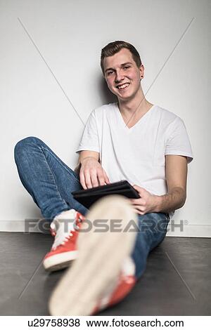 Teenage boy sitting on floor, using tablet View Large Photo Image Stock Photo - Teenage boy sitting on floor, using tablet. Fotosearch