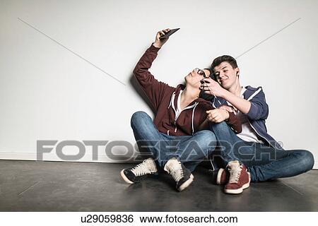 Teenage boys sitting cross legged leaning against wall using smartphones View Large Photo Image Stock Photograph - Teenage boys sitting cross legged leaning against wall using smartphones. Fotosearch