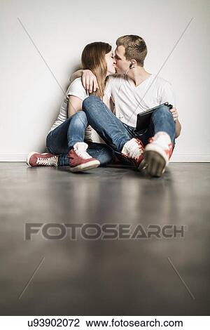 Teenage couple sitting on floor kissing View Large Photo Image Stock Image - Teenage couple sitting on floor kissing. Fotosearch