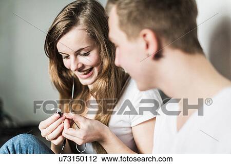 Teenage couple sitting on floor, holding earphones View Large Photo Image Stock Image - Teenage couple sitting on floor, holding earphones. Fotosearch