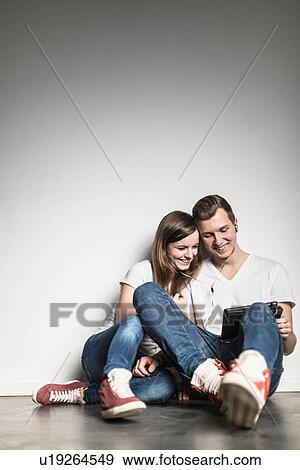 Teenage couple watching digital tablet, sharing earphones View Large Photo Image Stock Photo - Teenage couple watching digital tablet, sharing earphones. Fotosearch