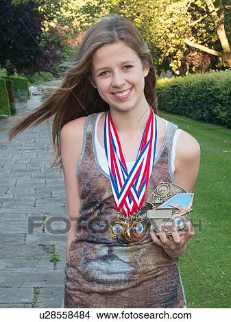 Picture - Teenage girl holding and wearing medals, portrait. Fotosearch