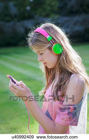 Stock Photo - Teenage girl listening to mp3 player outdoors. Fotosearch
