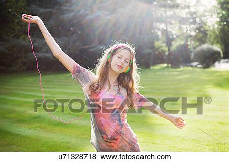 Stock Photo - Teenage girl listening to mp3 player and dancing. Fotosearch