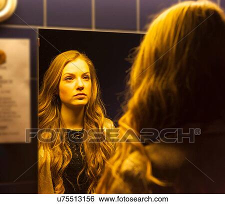Stock Photograph - Teenage girl looking at her reflection in mirror. Fotosearch