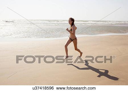 Stock Photograph - Teenage girl running along beach. Fotosearch