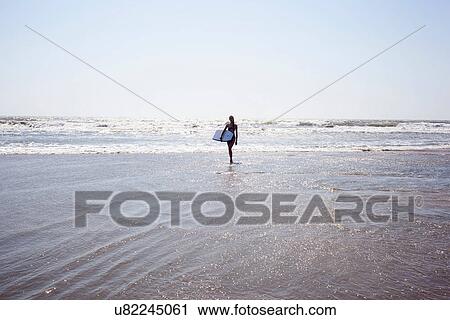 Teenage girl walking into sea with surfboard View Large Photo Image Stock Image - Teenage girl walking into sea with surfboard. Fotosearch