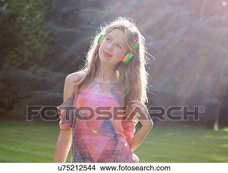 Teenage girl wearing headphones in sunlight View Large Photo Image Picture - Teenage girl wearing headphones in sunlight. Fotosearch