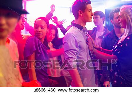 Stock Image - Teenage girl with hands on boy's chest at party. Fotosearch