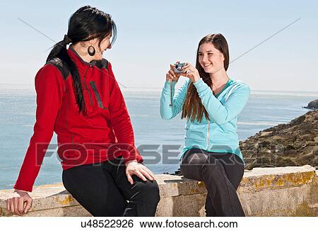 Teenager photographing friend at the coast View Large Photo Image Stock Photograph - Teenager photographing friend at the coast. Fotosearch