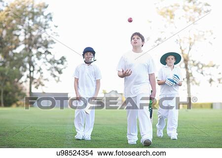 Picture - Three boys walking on cricket pitch. Fotosearch