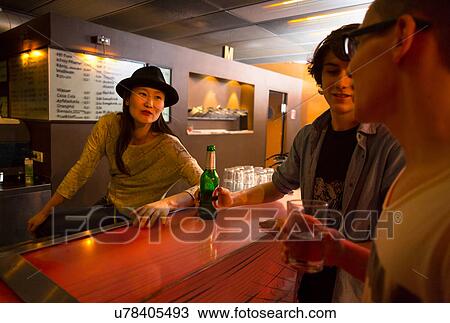 Three people sitting at bar with alcoholic drinks View Large Photo Image Stock Image - Three people sitting at bar with alcoholic drinks. Fotosearch