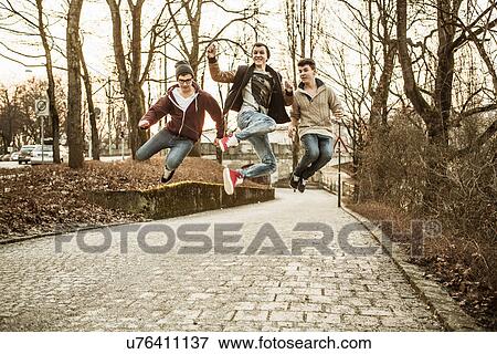 Three teenage boys jumping in park View Large Photo Image Stock Photo - Three teenage boys jumping in park. Fotosearch