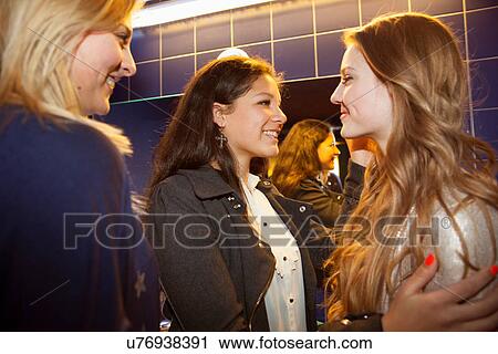 Stock Image - Three teenage girls chatting and smiling in toilets. Fotosearch