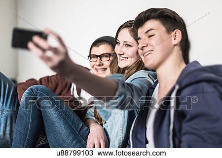 Three teenagers taking self portrait photograph using smartphone View Large Photo Image Stock Image - Three teenagers taking self portrait photograph using smartphone. Fotosearch