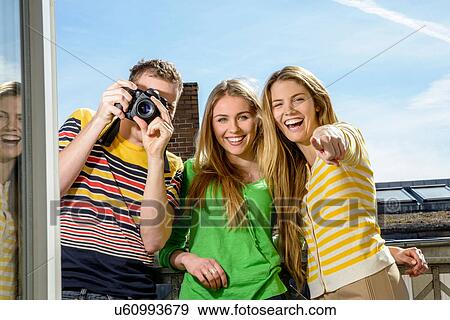 Stock Photo - Three young friends with camera on rooftop. Fotosearch