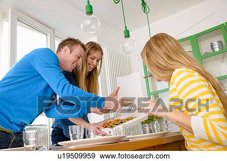 Stock Photo - Three young people serving pizza. Fotosearch