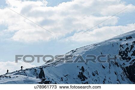 Stock Image - Two climbers silhouetted along snow covered ridge, Castell y Geifr, Snowdonia. Fotosearch