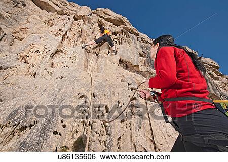 Stock Photograph - Two female rock climbers on cliff. Fotosearch