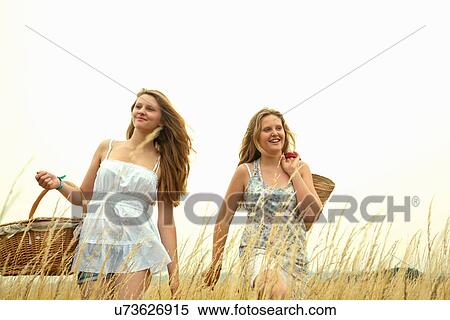 Two girls in a field with picnic baskets View Large Photo Image Stock Photography - Two girls in a field with picnic baskets. Fotosearch