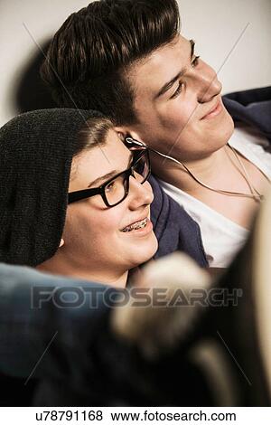 Stock Photo - Two teenage boys smiling and listening to earphones. Fotosearch