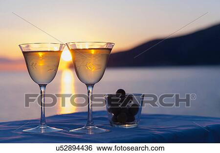 Stock Photograph - Two wine glasses and olives with sea in background. Fotosearch