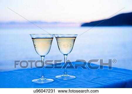 Stock Image - Two wine glasses with sea in background. Fotosearch