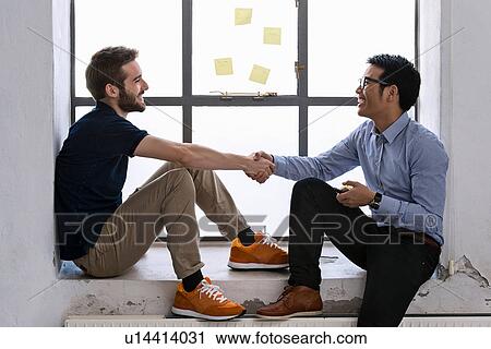 Two young male creatives shaking hands View Large Photo Image Stock Image - Two young male creatives shaking hands. Fotosearch