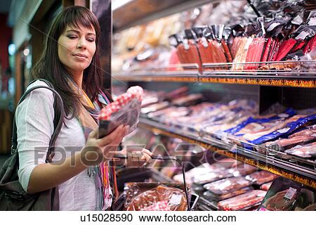 Stock Image - Woman choosing meat in butcher's shop. Fotosearch