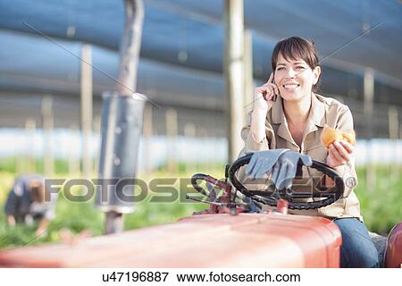 Stock Photo - Woman having lunch on vehicle in plant nursery. Fotosearch