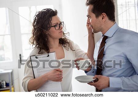 Woman holding clipboard and touching face of mature man wearing shirt and tie holding cup of coffee View Large Photo Image Stock Image - Woman holding clipboard and touching face of mature man wearing shirt and tie holding cup of coffee. Fotosearch