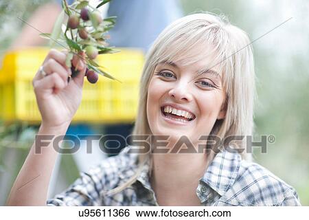Stock Photograph - Woman holding olives in olive grove, portrait. Fotosearch