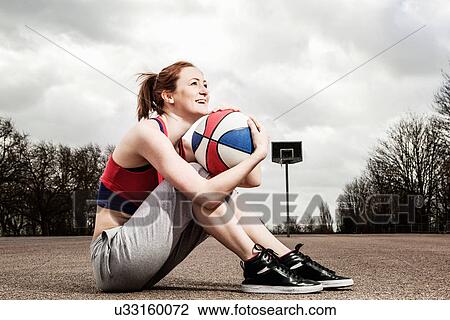 Stock Image - Woman hugging netball to chin. Fotosearch
