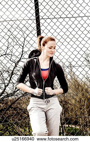 Woman in black hoodie leaning against fence View Large Photo Image Stock Image - Woman in black hoodie leaning against fence. Fotosearch
