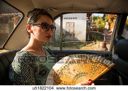 Picture - Woman in taxi holding fan. Fotosearch